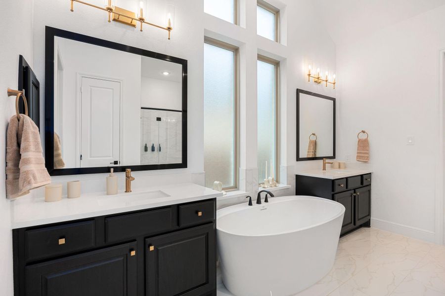 This well-appointed primary bathroom showcases dual vanities, a soaking tub, and a light-filled design.