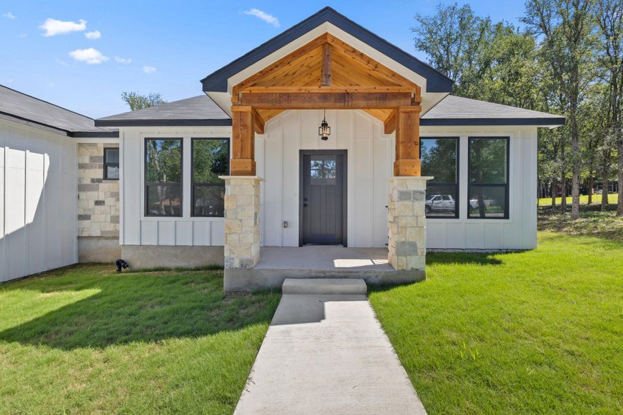 A welcoming entry features a gable roof with exposed wood beams and stone column accents. A welcoming entry features a gable roof with exposed wood beams and stone column accents.