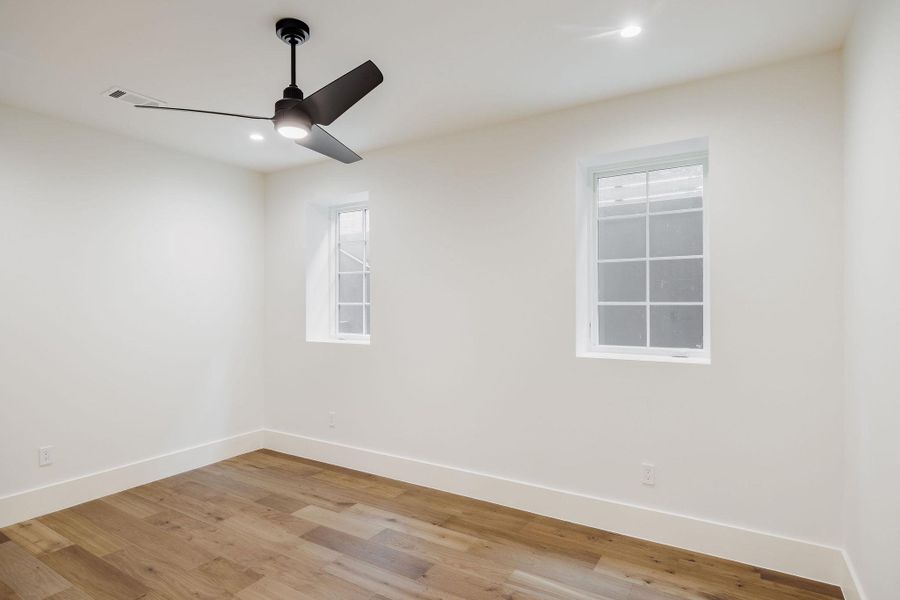 Crisp and bright, this flexible secondary bedroom features wide-plank wood floors, soft natural light, and a sleek modern ceiling fan, an inviting retreat for guests or a stylish home office. Crisp and bright, this flexible secondary bedroom features wide-plank wood floors, soft natural light, and a sleek modern ceiling fan, an inviting retreat for guests or a stylish home office.