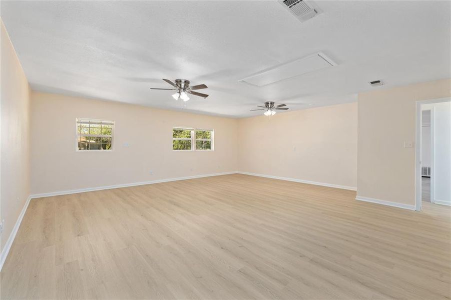 Empty room featuring a ceiling fan, attic access, and light wood finished floors