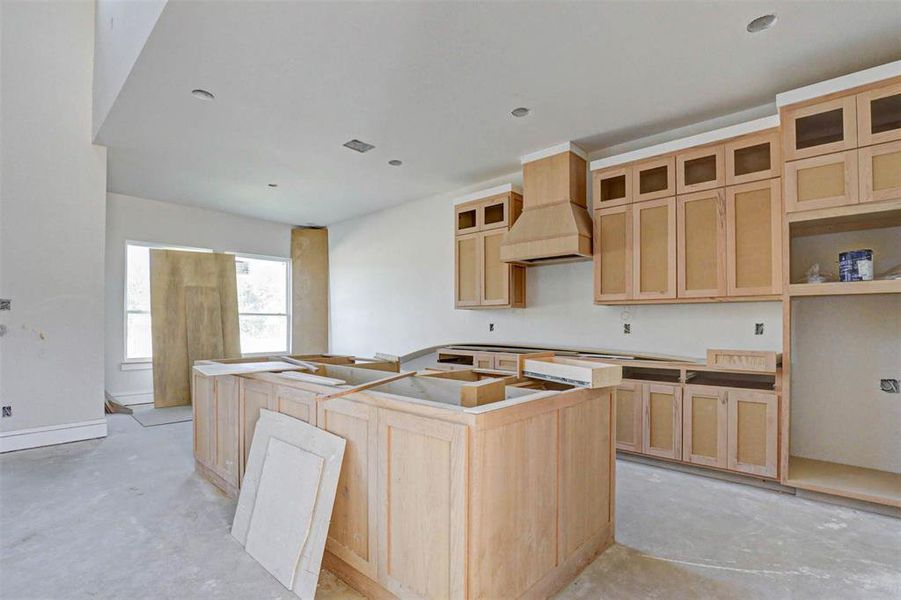 Kitchen featuring a kitchen island, custom range hood, and light brown cabinets