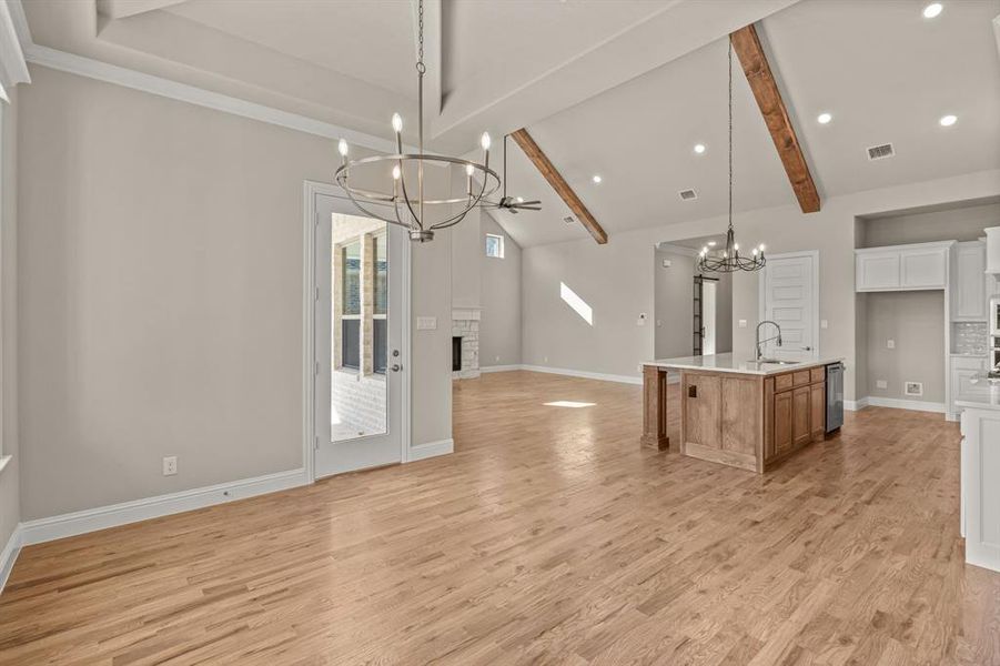 Kitchen with pendant lighting, sink, white cabinets, a kitchen island with sink, and a brick fireplace