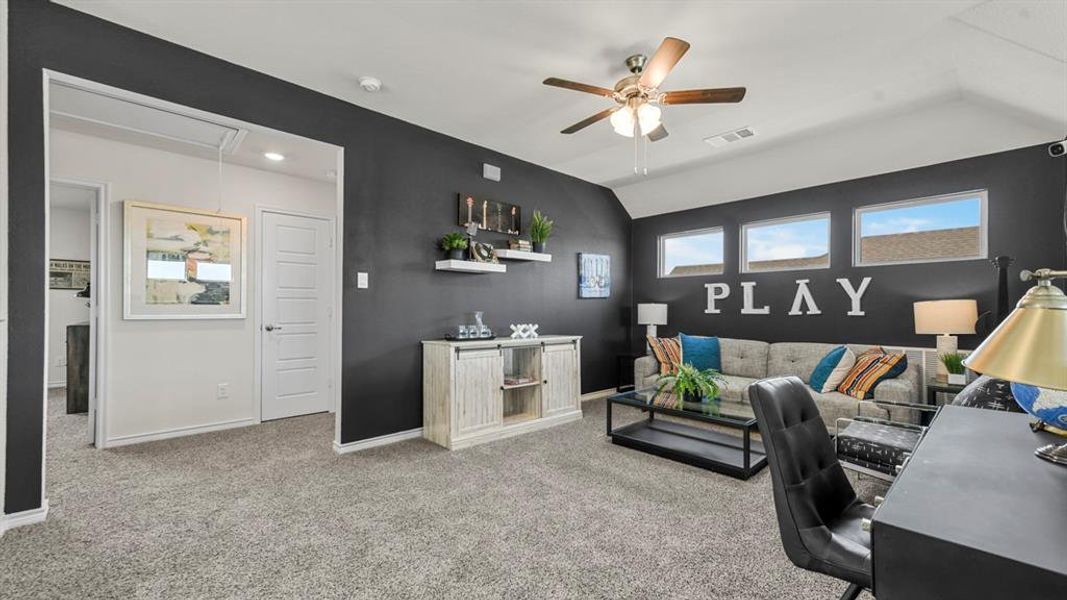 Spacious room featuring vaulted ceilings, a ceiling fan with integrated lighting, and carpet flooring
