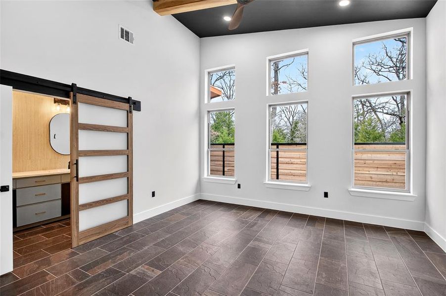 Empty room featuring a barn door, a ceiling fan, recessed lighting, and lofted ceiling
