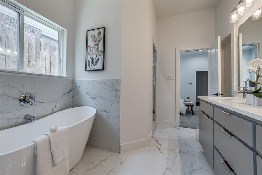 Bathroom featuring a tub, tile flooring, tile walls, and vanity