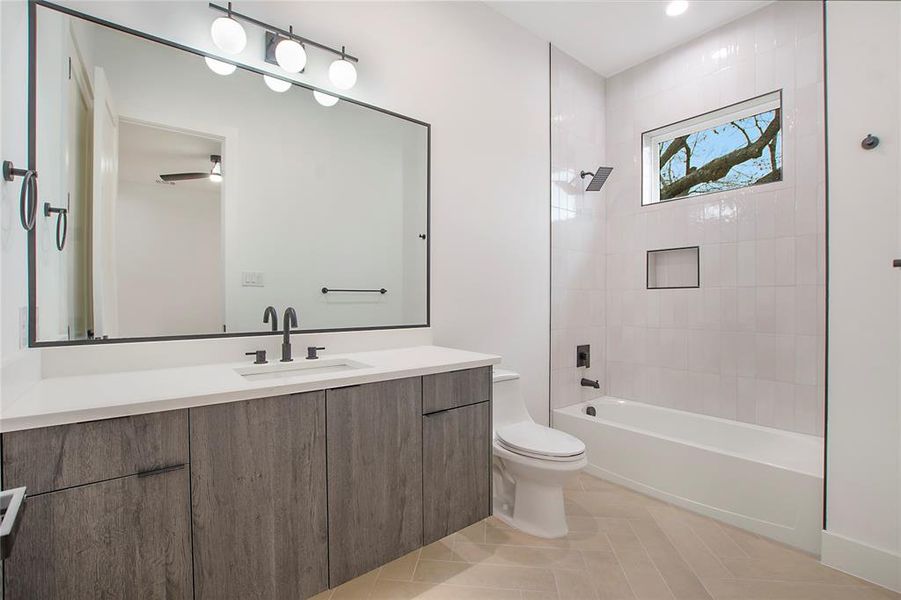 Full bathroom with ceiling fan, tiled shower / bath combo, tile patterned flooring, toilet, and vanity