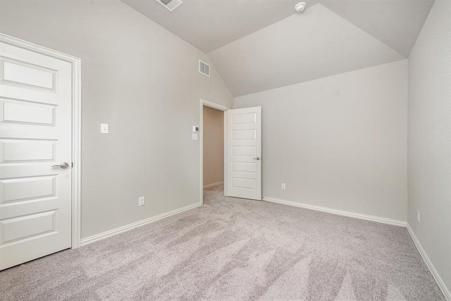 Carpeted spare room featuring lofted ceiling