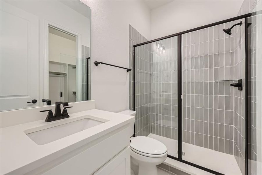 Bathroom featuring vanity, toilet, walk in shower, and tile patterned flooring