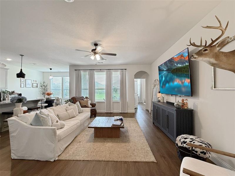 Living room with wood finished floors, arched walkways, and ceiling fan Living room with wood finished floors, arched walkways, and ceiling fan