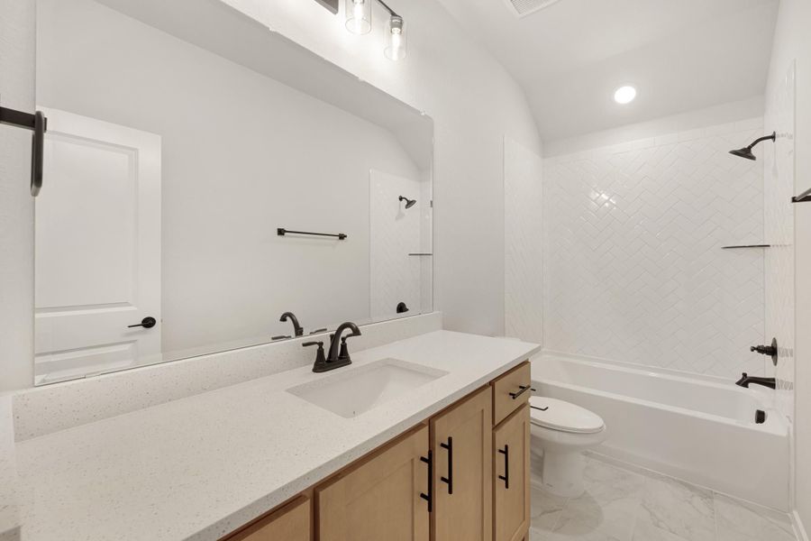 Bathroom with single vanity, quartz countertop, tub-shower combo with white herringbone tile, and black hardware fixtures Bathroom with single vanity, quartz countertop, tub-shower combo with white herringbone tile, and black hardware fixtures