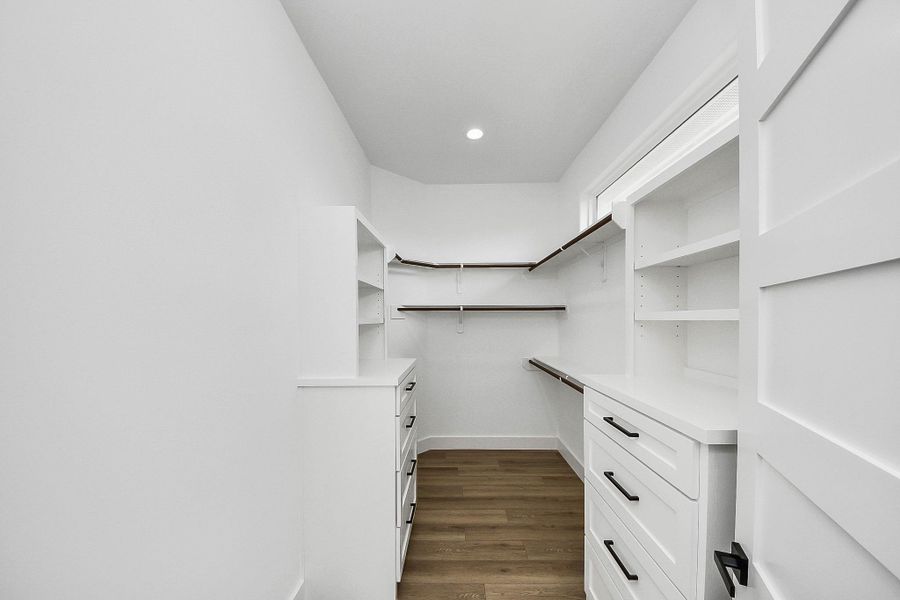Spacious primary closet with custom shelving, built-in drawers, and ample storage throughout.