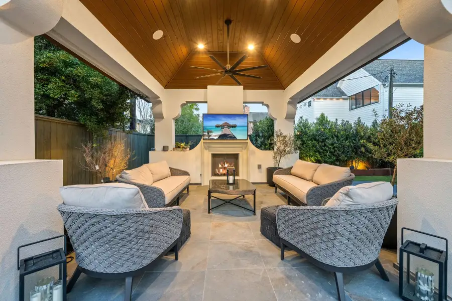 Covered outdoor living area with vaulted wood ceiling, fireplace, and mounted TV—designed for year-round comfort and effortless entertaining.