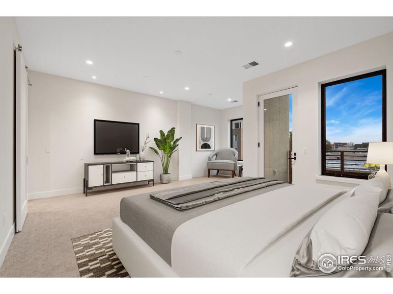 The primary bedroom faces south and features a reading nook and private deck that looks over Downtown Loveland. This photo has been virtually staged.