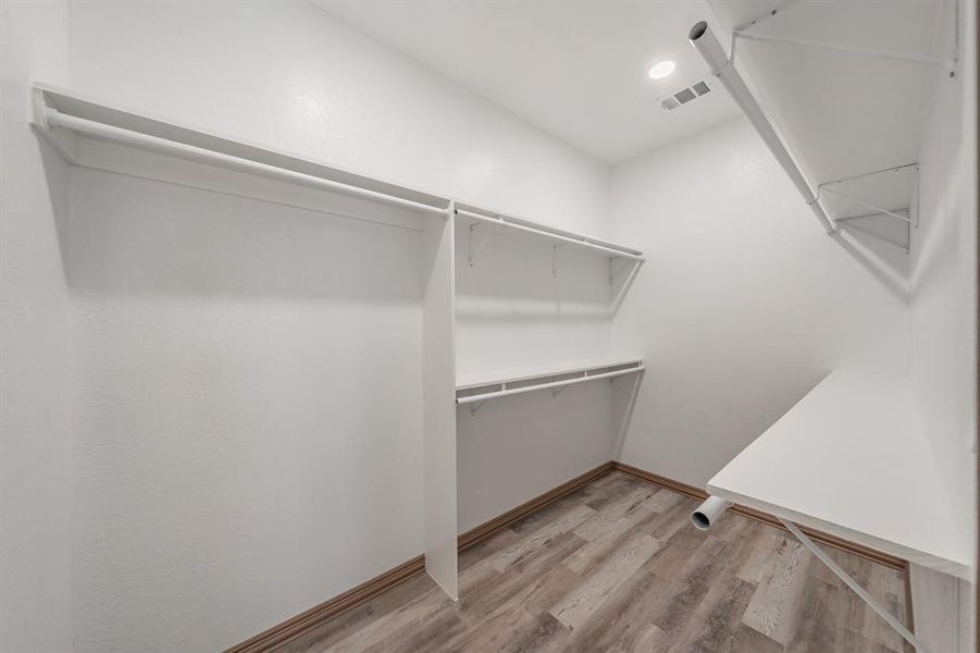 Spacious closet with light wood-style floors and visible vents