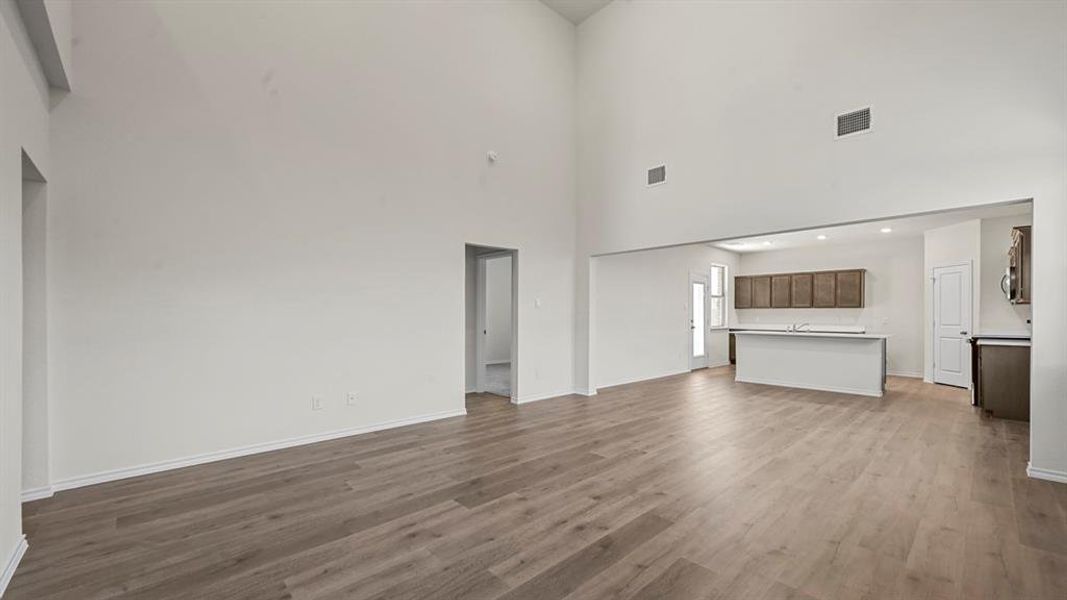 Expansive living space featuring high vaulted ceilings and light wood-finish flooring