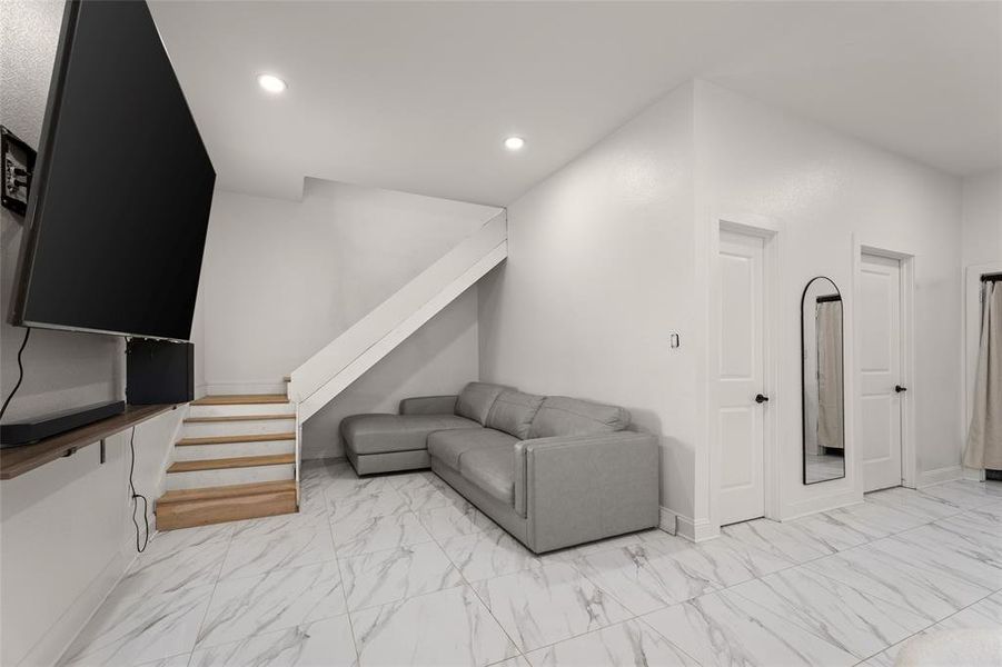 Living room featuring light marble finish floors, stairs, and recessed lighting