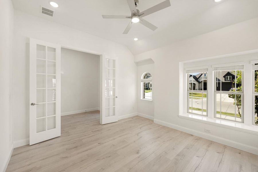 Empty room with light hardwood floors, French doors, vaulted ceiling, and ceiling fan