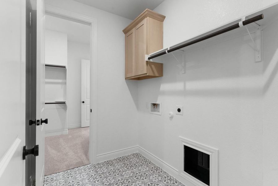 A well-appointed laundry room features patterned tile flooring and convenient built-in shelving.