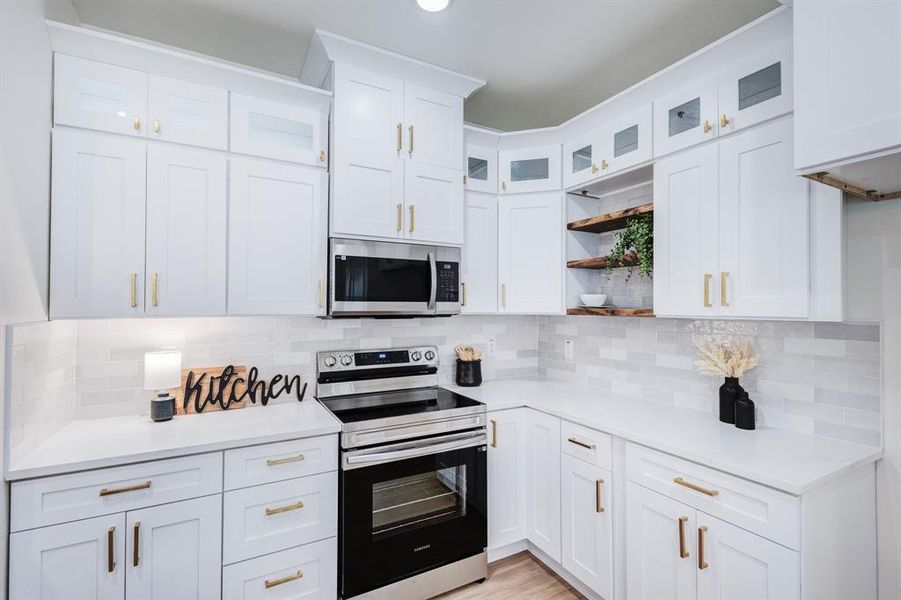 Kitchen featuring white cabinets, tasteful backsplash, light hardwood / wood-style flooring, and stainless steel appliances