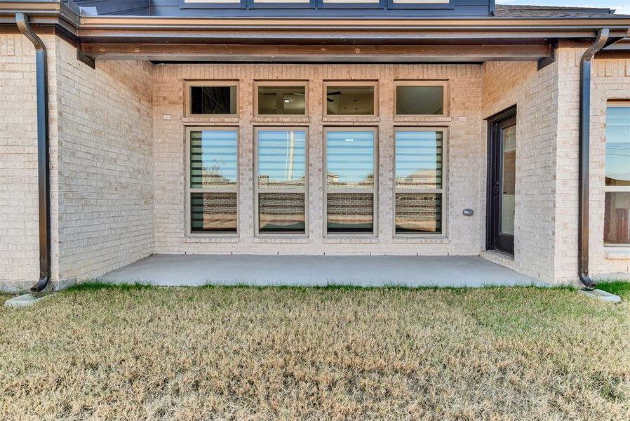 Property entrance featuring a patio area, brick siding, and a yard Property entrance featuring a patio area, brick siding, and a yard