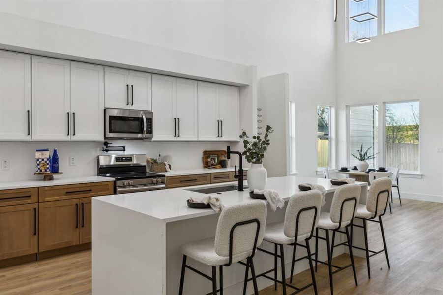 Kitchen featuring a kitchen breakfast bar, appliances with stainless steel finishes, sink, light wood-type flooring, and a kitchen island with sink