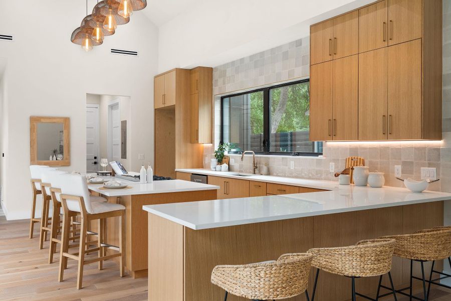Modern kitchen featuring light wood-finish cabinetry and white countertops