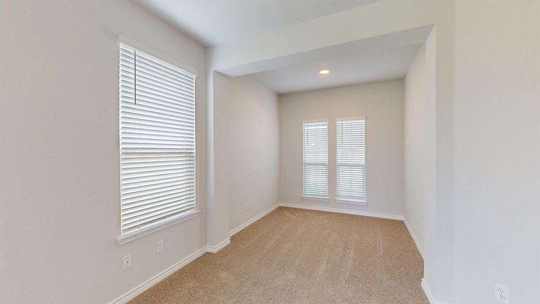 This room features neutral-toned carpet, light-colored walls, and windows fitted with blinds, providing natural light