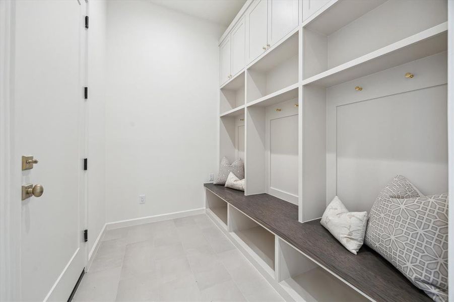 Custom built-in cabinetry in the mudroom provides organized storage space for coats, bags, and shoes, ensuring a clutter-free entrance from the garage.