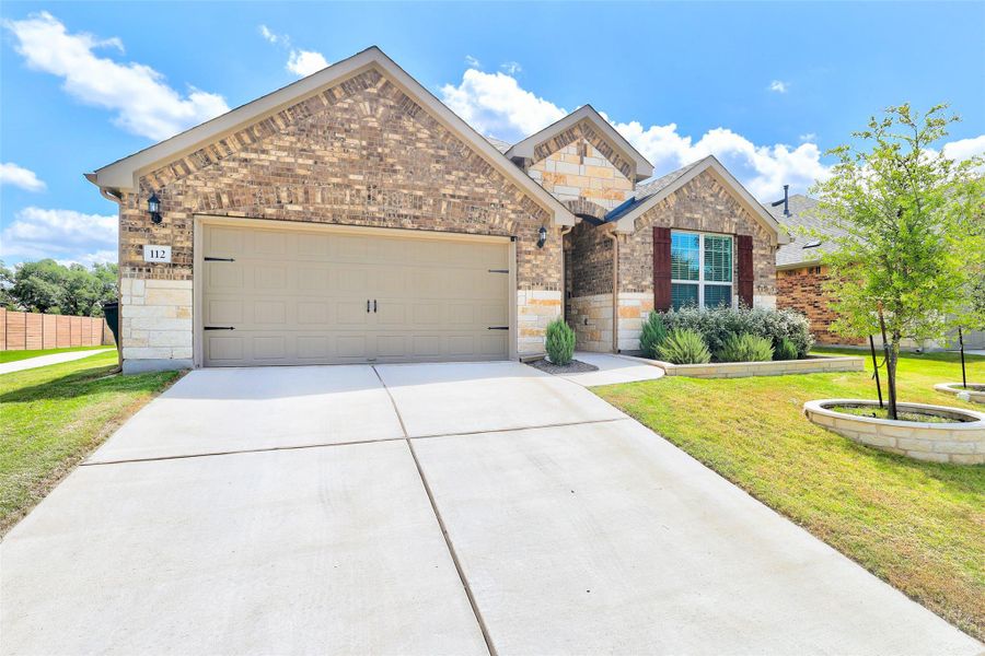 View of front facade featuring stone siding, a garage, driveway, and brick siding