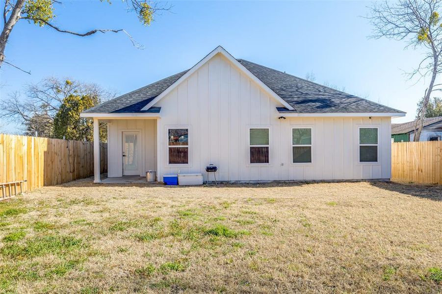 Rear view of property with a fenced backyard, a lawn, and board and batten siding