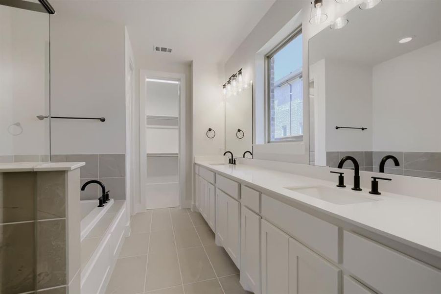 Bathroom featuring a dual vanity with white cabinetry, integrated sinks, and matte black fixtures