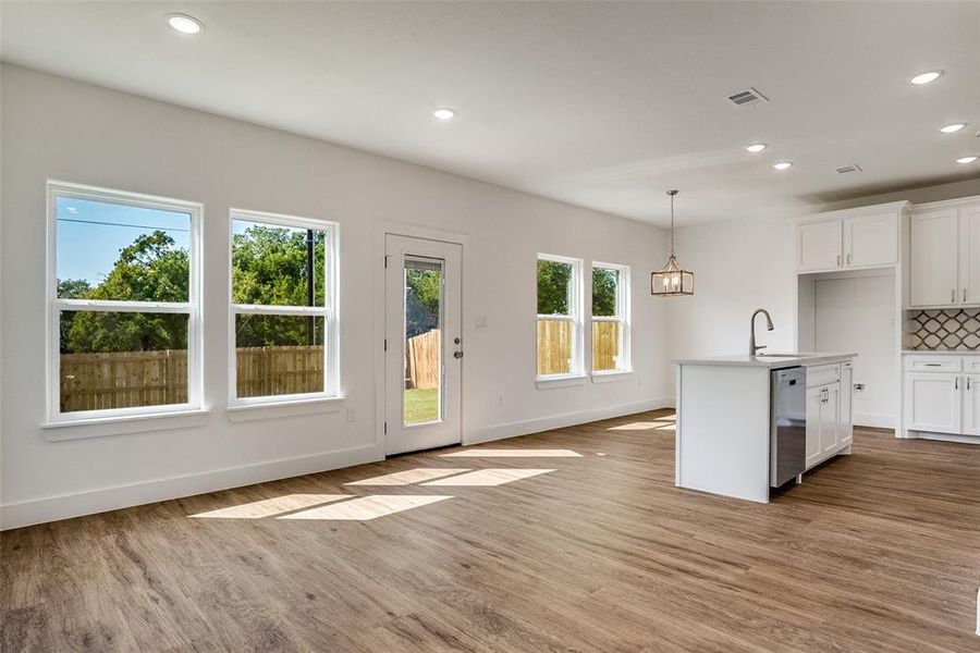 Kitchen with white cabinets, recessed lighting, a center island with sink, light wood-style flooring, and decorative light fixtures Kitchen with white cabinets, recessed lighting, a center island with sink, light wood-style flooring, and decorative light fixtures