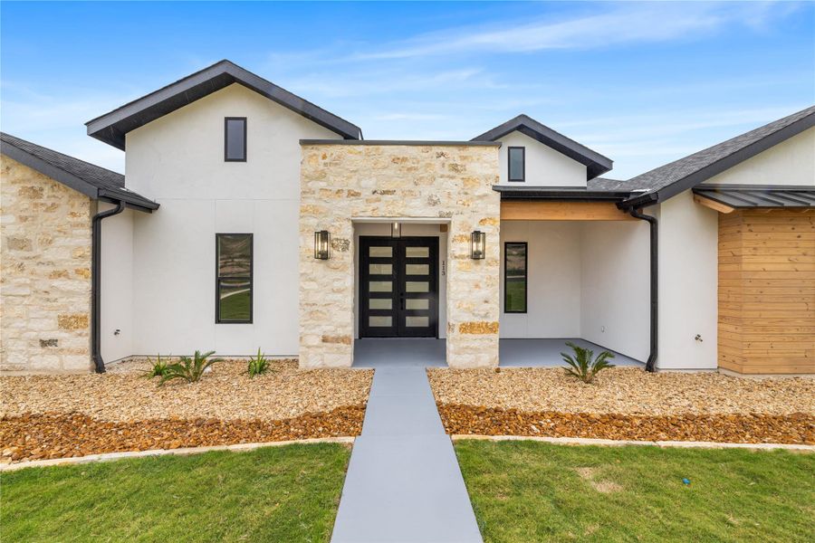 View of exterior entry with stone siding, stucco siding and landscaped front lawn. View of exterior entry with stone siding, stucco siding and landscaped front lawn.
