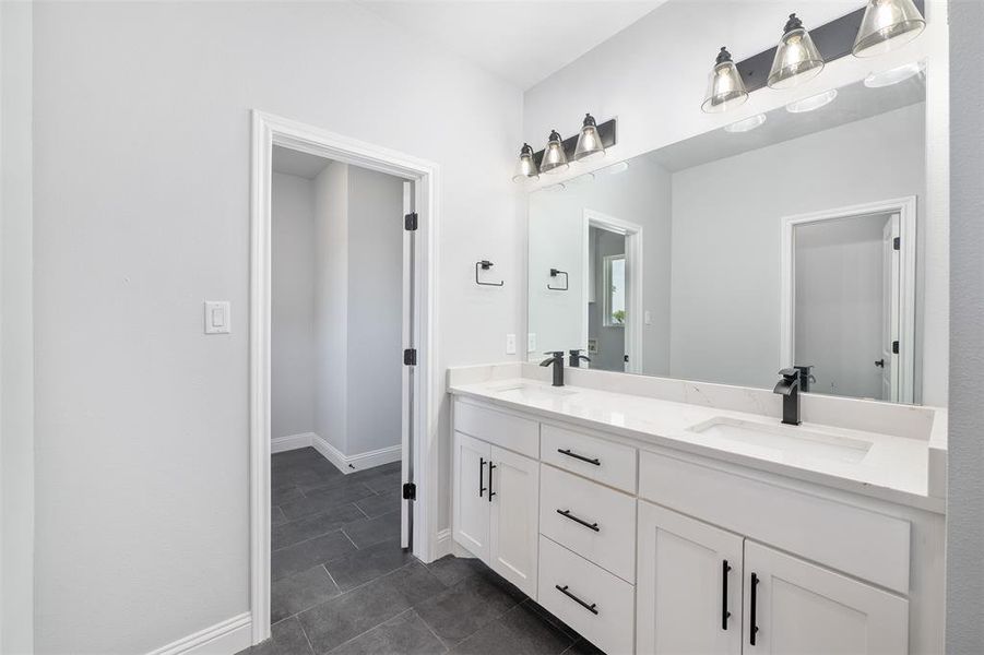 Full bathroom featuring double vanity, tile patterned flooring, baseboards, and a sink