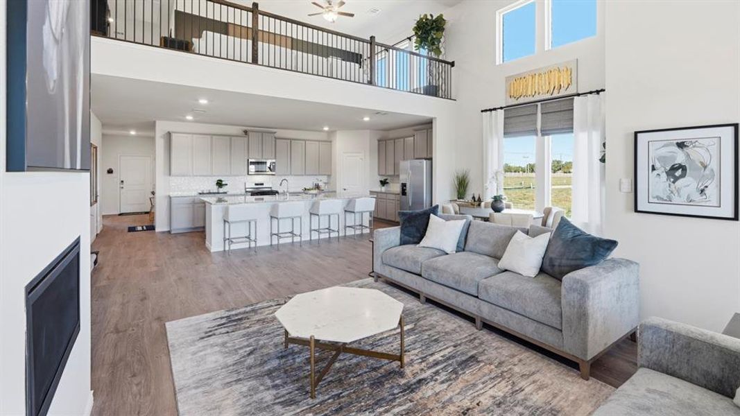 Living room featuring ceiling fan, wood finished floors, recessed lighting, and a high ceiling
