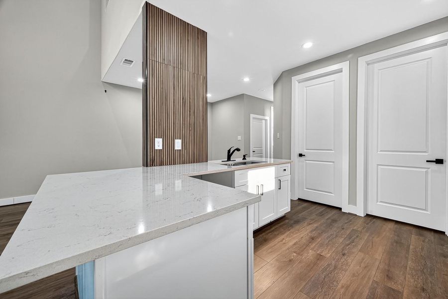 Gleaming countertops stretch generously, with bar seating for casual conversations, while crisp cabinetry forms a balance of elegance and everyday purpose.