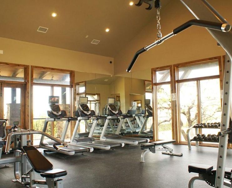 A well-equipped fitness area features large windows overlooking natural surroundings and durable rubber flooring.