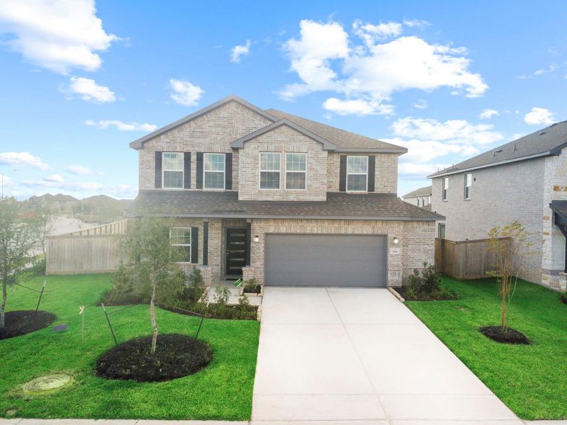 Front exterior view showcasing the home’s all-brick design, landscaped entry, and welcoming curb appeal that stands out beautifully within the community.