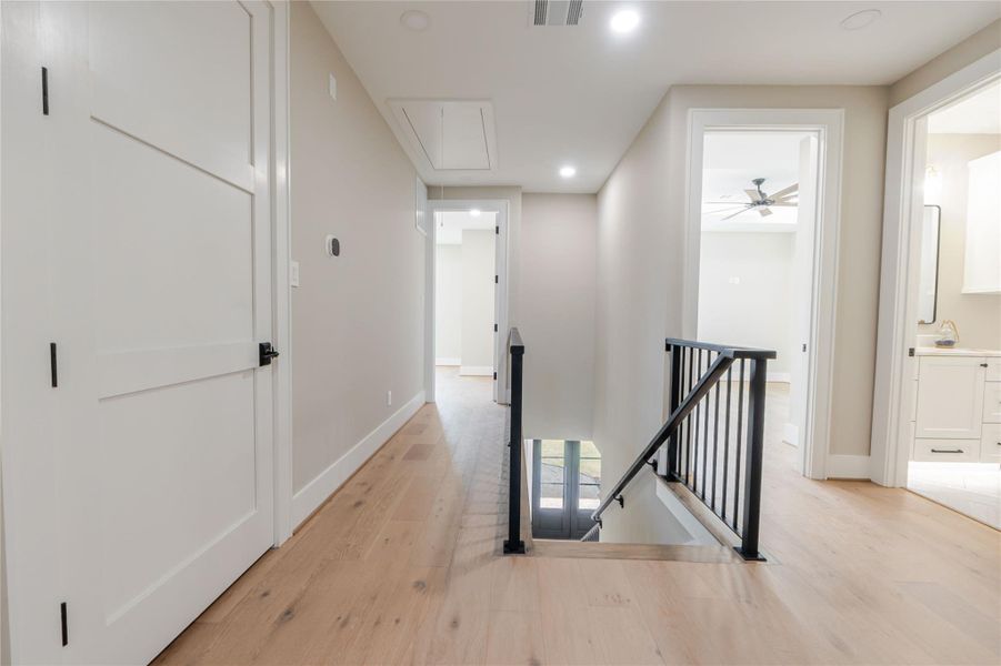 Hall with an upstairs landing, light wood finished floors, and recessed lighting
