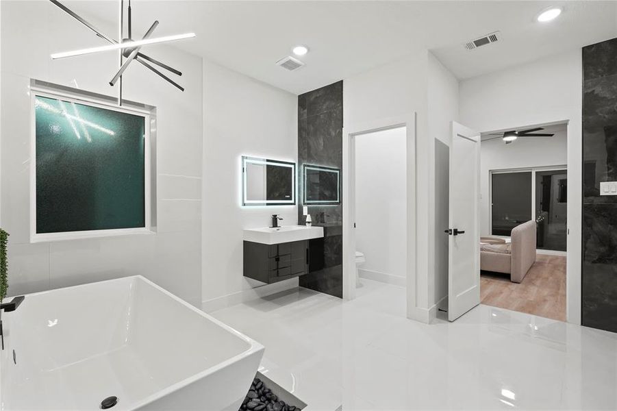 Ensuite bathroom with a soaking tub, vanity, a ceiling fan, and recessed lighting Ensuite bathroom with a soaking tub, vanity, a ceiling fan, and recessed lighting