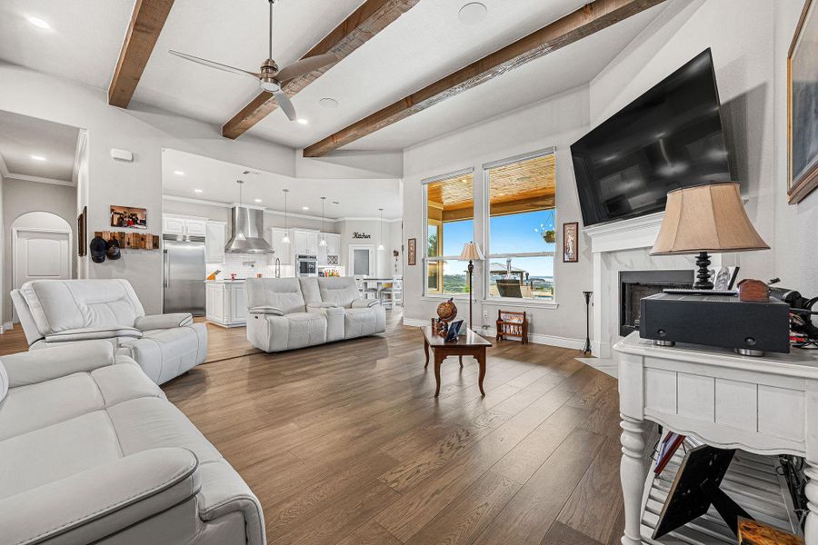 An open concept living area features exposed wood beams and a cozy fireplace, with large windows overlooking a scenic vista. An open concept living area features exposed wood beams and a cozy fireplace, with large windows overlooking a scenic vista.