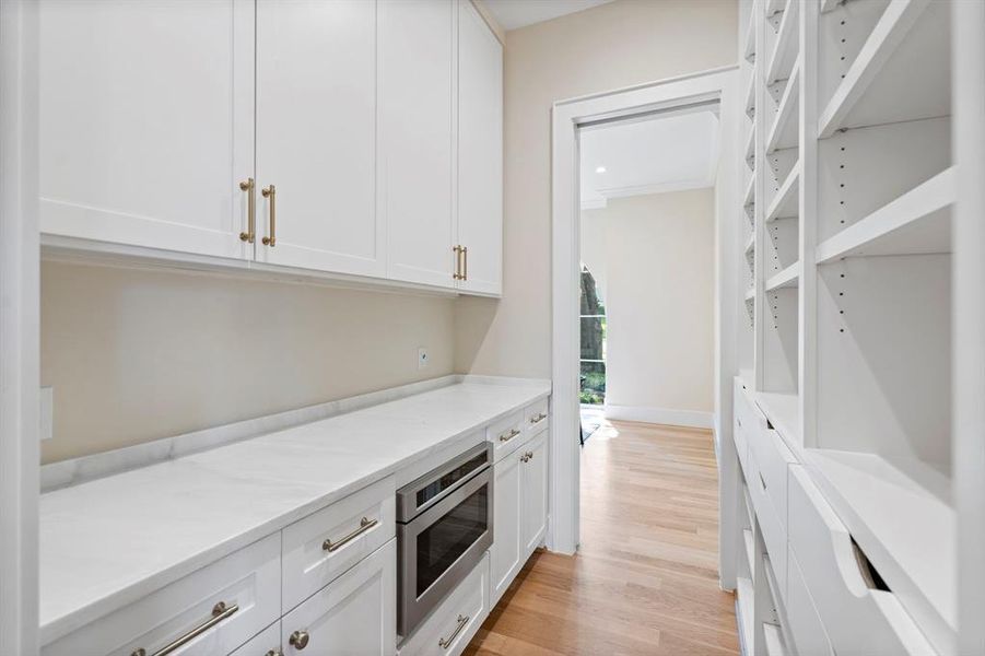 Bar featuring white cabinets, stainless steel oven, light wood-type flooring, and ornamental molding