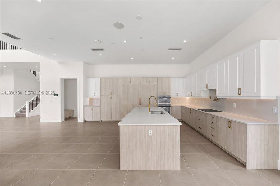 Spacious kitchen featuring an expansive center island, integrated appliances, extensive cabinetry, and tile flooring