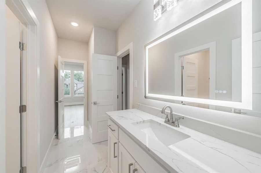 Bathroom with vanity, light marble finish flooring, and recessed lighting