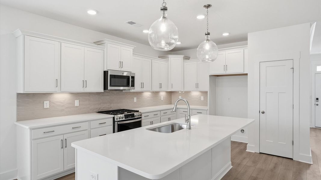Tasteful design meets functional luxury in this kitchen with a 9-foot island and modern pendant lighting
