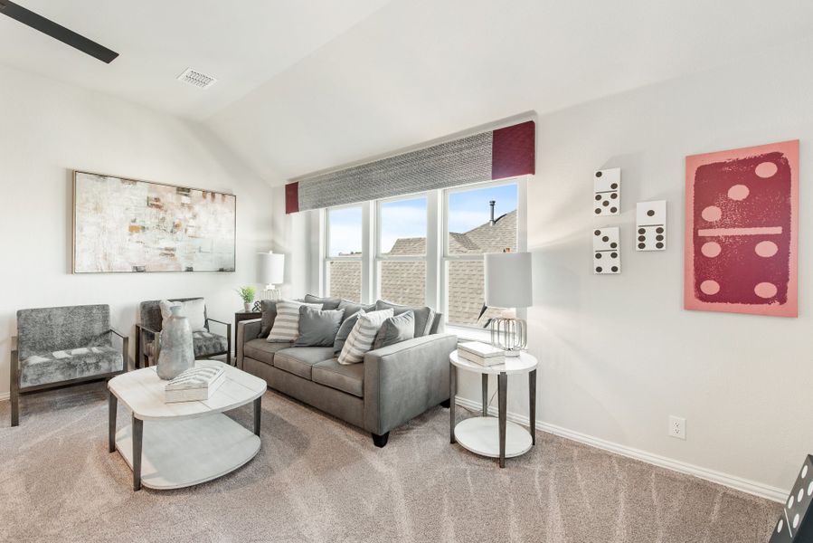 Living room with gray sofa, vaulted ceiling, carpet flooring, and large window with natural light