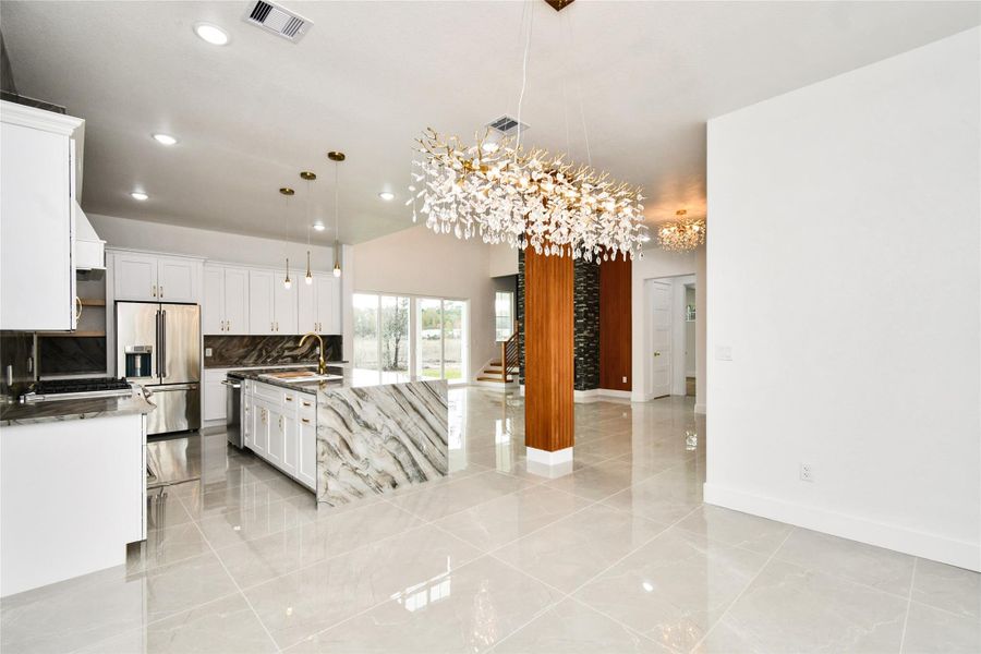 Expansive open-concept living at its finest. This sun-drenched great room features high-gloss porcelain tile flooring, a statement wood-clad pillar, and a stunning designer crystal chandelier that serves as a breathtaking centerpiece for the home.