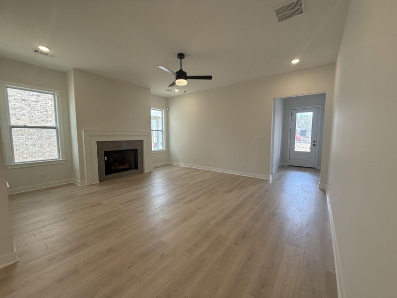Unfurnished living room with ceiling fan, a fireplace, recessed lighting, and light wood-style floors