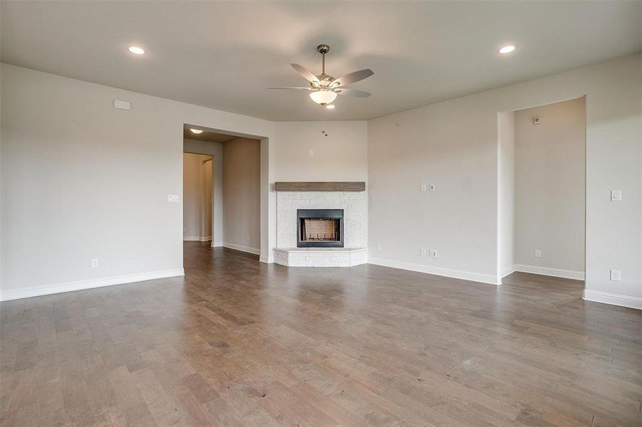 Unfurnished living room featuring hardwood / wood-style floors, a fireplace, and ceiling fan