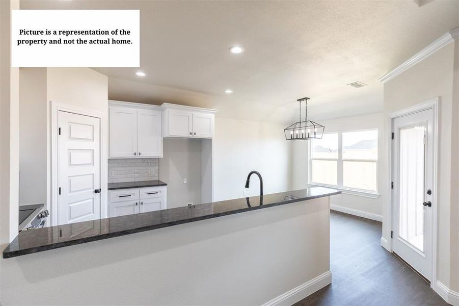 Open-concept kitchen and dining area featuring a breakfast bar with a dark countertop, white shaker cabinetry, a subway tile backsplash, and dark wood-finish flooring